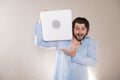 Young attractive man  holding white portable bluetooth speaker on gray background Royalty Free Stock Photo