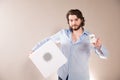 Young attractive man  holding white portable bluetooth speaker on gray background Royalty Free Stock Photo