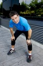 Young attractive man leaning exhausted after running session sweating taking a break to recover in urban street Royalty Free Stock Photo