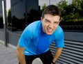 Young attractive man leaning exhausted after running session sweating taking a break to recover in urban street Royalty Free Stock Photo