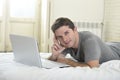 Young attractive man lying on bed or couch enjoying social networking using computer laptop at home Royalty Free Stock Photo