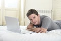 Young attractive man lying on bed or couch enjoying social networking using computer laptop at home Royalty Free Stock Photo