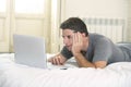 Young attractive man lying on bed or couch enjoying social networking using computer laptop at home Royalty Free Stock Photo