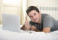 Young attractive man lying on bed or couch enjoying social networking using computer laptop at home Royalty Free Stock Photo