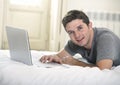 Young attractive man lying on bed or couch enjoying social networking using computer laptop at home Royalty Free Stock Photo