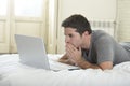 Young attractive man lying on bed or couch enjoying social networking using computer laptop at home wireless internet Royalty Free Stock Photo