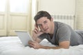 Young attractive man lying on bed or couch enjoying social networking using digital tablet computer internet at home Royalty Free Stock Photo