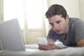 Young attractive man lying on bed or couch using mobile phone and computer laptop internet addict Royalty Free Stock Photo