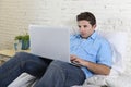 Young attractive man lying on bed enjoying social networking using computer laptop at home Royalty Free Stock Photo