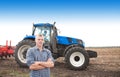 Young attractive man near a tractor. Concept of agriculture and field works. Royalty Free Stock Photo