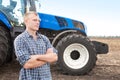 Young attractive man near a tractor. Concept of agriculture and field works. Royalty Free Stock Photo