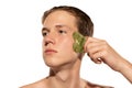 Young attractive man with perfect smooth skin, applying face massagers isolated over white studio background. Cosmetics