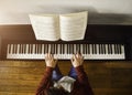 Young attractive man playing piano reading a score at the sunlight