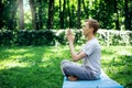 A young attractive man practices yoga in nature and meditates with his eyes closed in the lotus positio Royalty Free Stock Photo