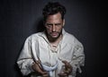 Young attractive man with scars from burns, holding a white theater like mask Royalty Free Stock Photo