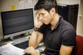 Young Attractive Man Sitting at Computer Desk Talking on Cell Phone Royalty Free Stock Photo