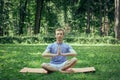 Young attractive man in sport clothes is meditating cupped in a meditation or prayer gesture with a pacified face in the park aga