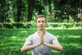 Young attractive man in sport clothes is meditating cupped in a meditation or prayer gesture with a pacified face