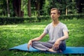 Young attractive man in sport clothes is meditating in the lotus position with a pacified face