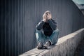 Unhappy depressed caucasian male sitting on urban street feeling