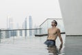 Young attractive man at the swimming pool in roof at skyscraper. Royalty Free Stock Photo