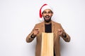 Young attractive man wearing Santa hat holding and pointing red shopping bag in christmas consumerism , December sale, buying xmas Royalty Free Stock Photo