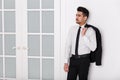 Young attractive man in a white shirt, tie and jacket hanging on his shoulder Royalty Free Stock Photo