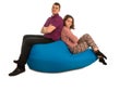 Young attractive man and woman sitting on blue beanbag sofa isolated on white background Royalty Free Stock Photo