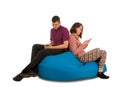 Young attractive man and woman sitting on blue beanbag sofa and Royalty Free Stock Photo