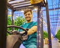Young attractive man working on electric forklift in greenhouse Royalty Free Stock Photo