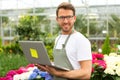 Young attractive man working at the plants nursery using laptop