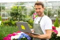 Young attractive man working at the plants nursery using laptop