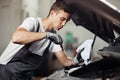 A young and attractive mechanic is checking an oil level of a car engine Royalty Free Stock Photo