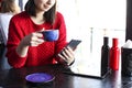 Happy young woman drinking cappuccino, latte, macchiato, tea, using tablet computer and talking on the phone in a coffee shop / ba Royalty Free Stock Photo