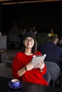 Happy young woman drinking coffee / tea and using tablet computer in a coffee shop Royalty Free Stock Photo