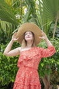 Young attractive millennial woman wearing a summer ruffled dress and holding with both hands an oversized straw hat Royalty Free Stock Photo