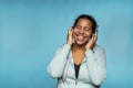 Young attractive mixed race woman enjoying music listening with headphones blue background