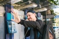 A young attractive modern man speaks at a payphone and welcomes with his hand. Communication concept. Royalty Free Stock Photo