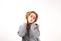 Beautiful red headed young woman posing, showing emotional facial expressions and making funny faces, dancing with big headphones.