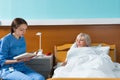 Young attractive nurse in uniform is reading a book for her patient who is lying in the hospital bed Royalty Free Stock Photo