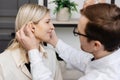 A young attractive otolaryngologist doctor gives a consultation to a female patient. A doctor explains how to wear a hearing aid