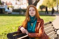 Young attractive pensive woman sitting on bench in the park