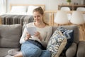 Smiling satisfied girl sitting on couch reading a book Royalty Free Stock Photo