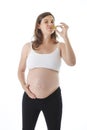 Young attractive pregnant woman holding her big belly in one hand and eating pickle happy Royalty Free Stock Photo