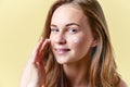 Young attractive redhead woman applying moisturiser face cream, smiling and looking at camera. Beauty, skincare. Royalty Free Stock Photo