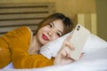Young attractive and relaxed Asian Korean girl using mobile phone at home bedroom enjoying internet online dating app or social Royalty Free Stock Photo