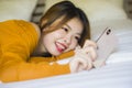 Young attractive and relaxed Asian Korean girl using mobile phone at home bedroom enjoying internet online dating app or social Royalty Free Stock Photo