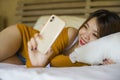 Young attractive and relaxed Asian Korean girl using mobile phone at home bedroom enjoying internet online dating app or social Royalty Free Stock Photo