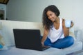 Young attractive and relaxed hispanic student woman sitting at home sofa couch networking with laptop computer drinking coffee or Royalty Free Stock Photo