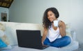 Young attractive and relaxed latin American student woman sitting at home sofa couch networking with laptop computer drinking coff Royalty Free Stock Photo